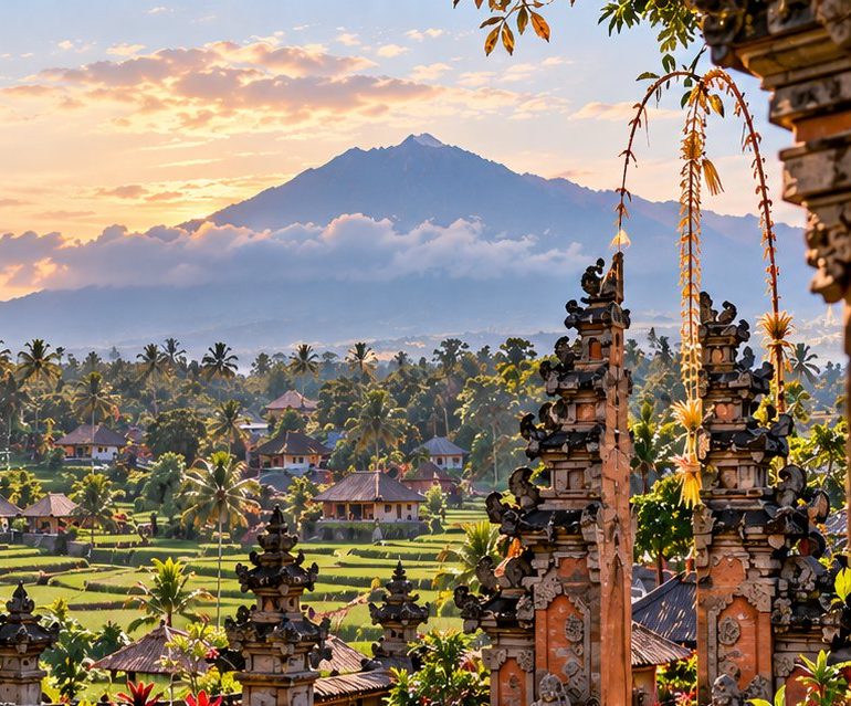 A carved Balinese temple gate in front of Mount Agung at golden hour, with rice terraces below